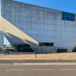 Rem Koolhaas’s Casa da Música showcasing a brutalist concrete commercial building with composite materials, featuring bold geometric forms and extensive daylighting in an urban design context.