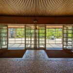 Ricardo Vieira de Melo and Eduardo Rebelo’s Complexo Pedagógico II at Universidade do Minho showcases a modern design with extensive glass façades, composite material flooring, wood-stained ceiling elements, and tiled floorings that enhance natural daylighting and provide shaded interior spaces.