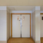 Ricardo Vieira de Melo and Eduardo Rebelo’s Complexo Pedagógico II at Universidade do Minho showcasing a modern interior with wood-stained hardwood flooring, composite material ceiling, and sleek wooden doors.