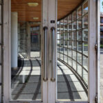Ricardo Vieira de Melo and Eduardo Rebelo’s Complexo Pedagógico II at Universidade do Minho showcasing a modern building with composite material flooring, metal and glass doors, and wood-stained elements integrated into the façade.