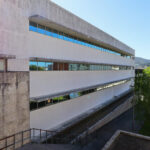 Unknown Architect’s Escola de Engenharia I at Universidade do Minho showcasing a concrete façade with large windows for daylighting, surrounded by palm trees, serving as a corporate headquarters.