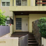 Unknown Architect’s House Rua Faial showcasing a modern residential design with concrete walls, composite material balcony, exterior stairs, and a minimalist door.