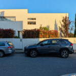 Unknown Architect’s Villa II Rua da Vilarinha showcasing a modern residential design with a sleek glass façade and integrated green rooftop, visible alongside a luxury family car parked in the driveway.