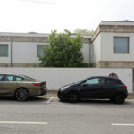 Unknown Architect’s Villa Rua do Padrão showcasing a modern residential design with a sleek glass façade and integrated green rooftop, visible alongside a parked personal luxury car with detailed automotive exterior features.