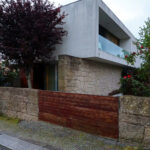 Unknown Architect’s Villa Tv. Cavada showcasing a sloped design with composite material walls, concrete elements, and a combination of brick and stone wall textures.