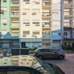 Colorful buildings of Rua António José da Costa featuring vibrant façades, multiple windows, residential apartments, and parked cars in a lively neighborhood setting.