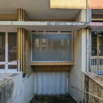 Colorful Buildings of Rua António José da Costa by Unknown Architect showcasing vibrant yellow walls, wood-stained balconies, and a mix of concrete, metal, and composite materials.