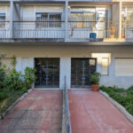 Colorful residential buildings of Rua António José da Costa featuring concrete balconies, shaded courtyards, fenced yards, and daylighting elements in a condominium setting.