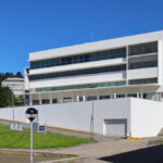 Unknown Architect’s Complexo Pedagógico III at Universidade do Minho showcasing a modern commercial building with a glass façade and structured urban design elements.