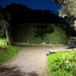 Unknown Architect’s Shower House Parque da Cidade showcasing a modern structure integrated with landscaped gardens, shaded walkways, hedges, and botanical elements creating a harmonious blend with nature.