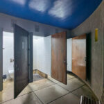 Unknown Architect’s Shower House Parque da Cidade showcasing concrete walls and ceiling, composite material flooring with tile patterns, and modern light fixtures.