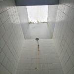 Shower House Parque da Cidade by Unknown Architect showcasing a grey composite material ceiling with concrete and plaster finishes, featuring tiled surfaces and ample daylighting.