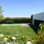 Nuno Graça Moura’s 4 Villas at Bom Sucesso Resort showcasing modern architecture with landscaped gardens, green lawns, shrubs, and extensive groundcover surrounding the villas.