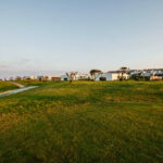 Nuno Graça Moura’s 8 Villas at Bom Sucesso Resort showcasing modern minimalist structures with flat roofs and large glass façades set within a natural grassland environment.