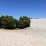 Nuno Graça Moura’s 8 Villas at Bom Sucesso Resort showcasing modern concrete driveways and walkways with flagstone paths, landscaped surroundings, and shaded areas creating a harmonious outdoor environment.