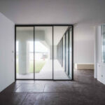 Nuno Graça Moura’s 8 Villas at Bom Sucesso Resort showcasing modern architecture with composite material flooring, expansive glass walls for daylighting and transparency, and clean, minimalist ceiling design.