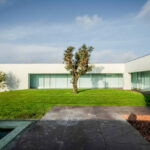 Nuno Graça Moura’s 8 Villas at Bom Sucesso Resort showcasing modern landscaping with manicured lawns, hedges, and garden design surrounding minimalist villa structures.