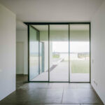 Nuno Graça Moura’s 8 Villas at Bom Sucesso Resort showcasing composite material flooring, large glass home doors, and daylighting that emphasizes transparency and clean modern design.