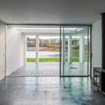Nuno Graça Moura’s Bar Code 1 - 30 Row Houses at Bom Sucesso Resort showcasing interior design with concrete flooring, composite material doors, glass elements, and daylighting through large windows.