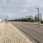 Nuno Graça Moura’s Bar Code 1 - 30 Row Houses at Bom Sucesso Resort showcasing a linear arrangement of modern row houses with clean lines, flat roofs, and integrated walkways alongside a paved road surface and sidewalks.