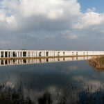 Nuno Graça Moura’s Bar Code 1 - 30 Row Houses at Bom Sucesso Resort showcasing modern row houses with reflective glass façades overlooking a wetland reservoir and freshwater marsh.