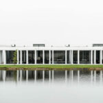 Nuno Graça Moura’s Bar Code 1 - 30 Row Houses at Bom Sucesso Resort showcasing modern row houses with reflective glass façades overlooking a tranquil reflecting pool and pond.
