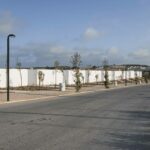 Nuno Graça Moura’s Bar Code 2 - 12 Row Houses at Bom Sucesso Resort showcasing modern row houses with clean lines, asphalt road surface, sidewalks, street lights, and electrical supply poles along the thoroughfare.