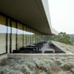 Nuno Graça Moura’s Golf Clubhouse at Bom Sucesso Resort showcasing a modern structure integrated into a hillside slope with expansive glass façades overlooking the hinterland.