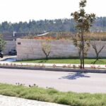 Nuno Graça Moura’s Golf Clubhouse at Bom Sucesso Resort showcasing a landscaped garden with concrete and flagstone walkways, surrounded by lush plants and a well-designed driveway path.