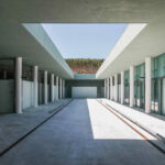 Nuno Graça Moura’s Golf Maintenance Building at Bom Sucesso Resort showcasing concrete columns, composite material flooring, tiled surfaces, and engineered daylighting with shaded ceiling elements.