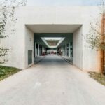 Nuno Graça Moura’s Golf Maintenance Building at Bom Sucesso Resort showcasing a symmetrical concrete structure with composite material elements, a shaded walkway, landscaped courtyard, and daylighting design features.