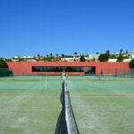 Nuno Graça Moura’s Tennis Club at Bom Sucesso Resort showcasing multiple tennis courts with artificial turf, nets, and modern sports venue design elements.