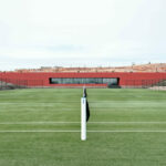 Nuno Graça Moura’s Tennis Club at Bom Sucesso Resort showcasing a modern sports venue with artificial turf courts, net structures, and open stadium seating.
