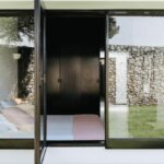 Antonio Corte-Real’s Maison de Vacances Esposende showcasing a natural material exterior with large sliding glass doors, shaded areas, and abundant daylighting.