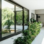 Antonio Corte-Real’s Maison de Vacances Esposende showcasing an interior courtyard with abundant daylighting, glass doors opening to landscaped gardens, shaded seating areas, and modern home plants enhancing the contemporary design.