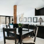 Antonio Corte-Real’s Maison de Vacances Esposende interior showcasing modern furniture, wooden flooring, minimalist ceiling design, a central table with surrounding chairs, and contemporary light fixtures.