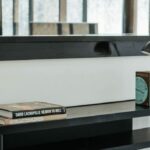 Antonio Corte-Real’s Maison de Vacances Esposende interior showcasing modern shelving units, grey flooring, minimalist furniture, a living room with houseplants, and framed artwork.