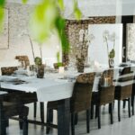 Antonio Corte-Real’s Maison de Vacances Esposende interior showcasing modern wood flooring, minimalist furniture including chairs and a dining table, with natural lighting highlighting the open kitchen and dining area.