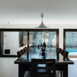 Antonio Corte-Real’s Maison de Vacances Esposende interior showcasing wooden flooring, ceiling beams, minimalist furniture, and a dining table in a modern, open-plan living space.