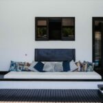 Antonio Corte-Real’s Maison de Vacances Esposende interior showcasing modern wood flooring, minimalist furniture including a couch with cushions and throw pillows, and contemporary lighting fixtures.