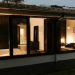 Antonio Corte-Real’s Maison de Vacances Esposende showcasing a modern interior design with wooden stained walls, glass doors, and a ceiling featuring natural light and shaded elements.