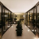 Antonio Corte-Real’s Maison de Vacances Esposende interior showcasing clean living room design with wooden flooring, ceiling light fixtures, and houseplants in flowerpots enhancing the eco-friendly atmosphere.
