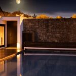 Antonio Corte-Real’s Maison de Vacances Esposende showcasing a modern villa with a composite material façade, illuminated landscape lighting, a swimming pool reflecting the dusk sky, and sleek resort-style design elements.