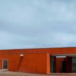 Atelier dos Remédios, Madalena Cardoso de Menezes, and Francisco Teixeira Bastos’ 10 Casa O Villas at Bom Sucesso Resort featuring cylindrical concrete structures with composite materials under an orange sky.