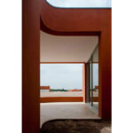 Atelier dos Remédios, Madalena Cardoso de Menezes, and Francisco Teixeira Bastos’ 10 Casa O Villas at Bom Sucesso Resort featuring a modern design with red and orange composite materials, wood-stained elements, and distinctive geometric assemblies.