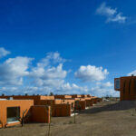 Atelier dos Remédios, Madalena Cardoso de Menezes, and Francisco Teixeira Bastos’ 18 Red Row Houses at Bom Sucesso Resort featuring a series of connected red brick façades with modern window assemblies and minimalist building materials.
