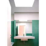 Atelier dos Remédios, Madalena Cardoso de Menezes, and Francisco Teixeira Bastos’ 18 Red Row Houses at Bom Sucesso Resort featuring tiled surfaces, modern light fixtures, and visible plumbing fixtures emphasizing clean, minimalist design.