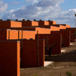 Atelier dos Remédios, Madalena Cardoso de Menezes, and Francisco Teixeira Bastos’ 18 Red Row Houses at Bom Sucesso Resort featuring orange composite material façades with sharp shadows highlighting the modern building assembly.