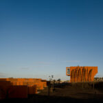 Atelier dos Remédios, Madalena Cardoso de Menezes, and Francisco Teixeira Bastos’ 18 Red Row Houses at Bom Sucesso Resort featuring vibrant orange façades with linear row house assemblies illuminated by morning sunlight in a landscaped setting.
