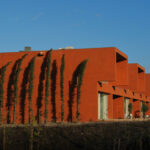 Atelier dos Remédios, Madalena Cardoso de Menezes, and Francisco Teixeira Bastos’ design of the 18 Red Row Houses at Bom Sucesso Resort featuring vibrant orange geraniums and modern red façades with clean lines.